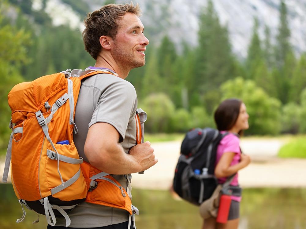 A man and a woman wearing backpacks hiking outdoors, one of the many things to do in Ashe County NC.